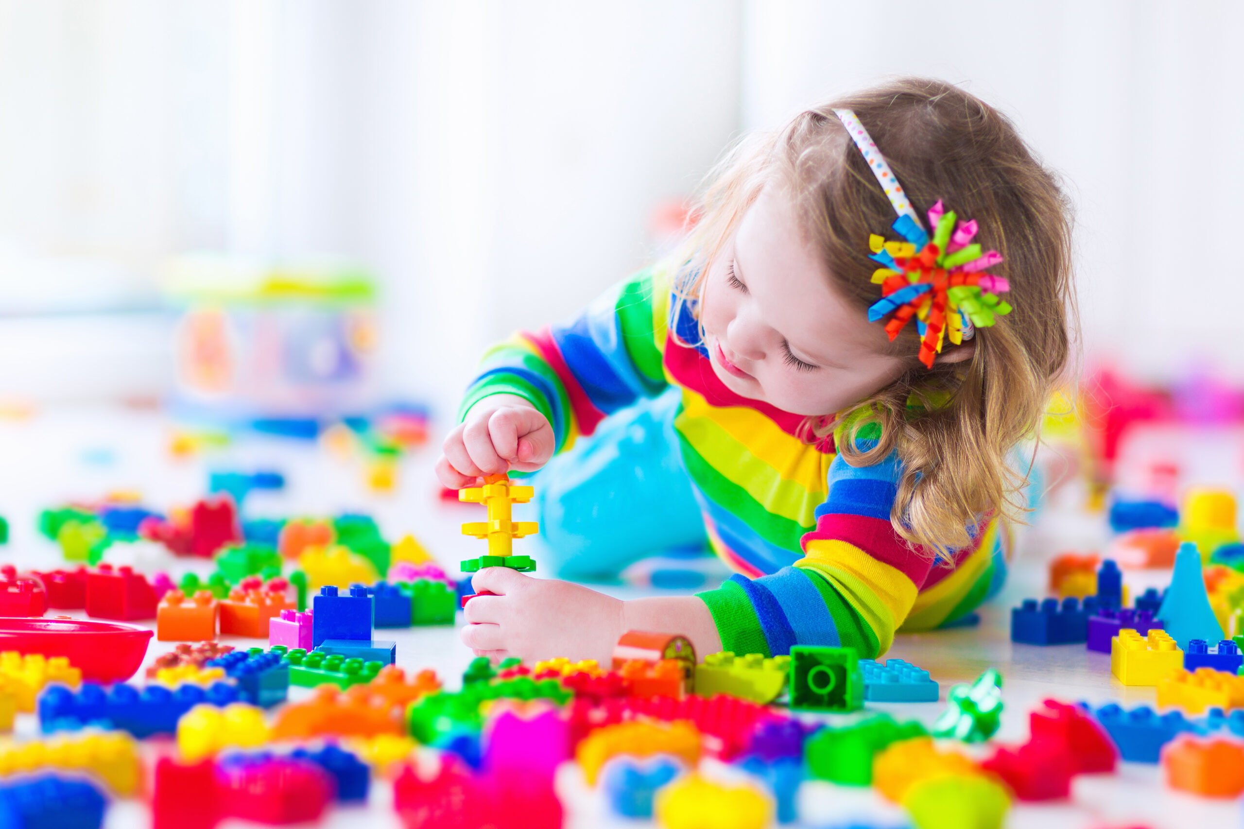 Little girl playing with colorful toy blocks