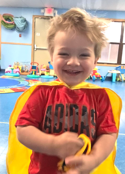 Our Emerging Toddler Program in action Toddler smiling in a superhero cape at Creative Kids Academy