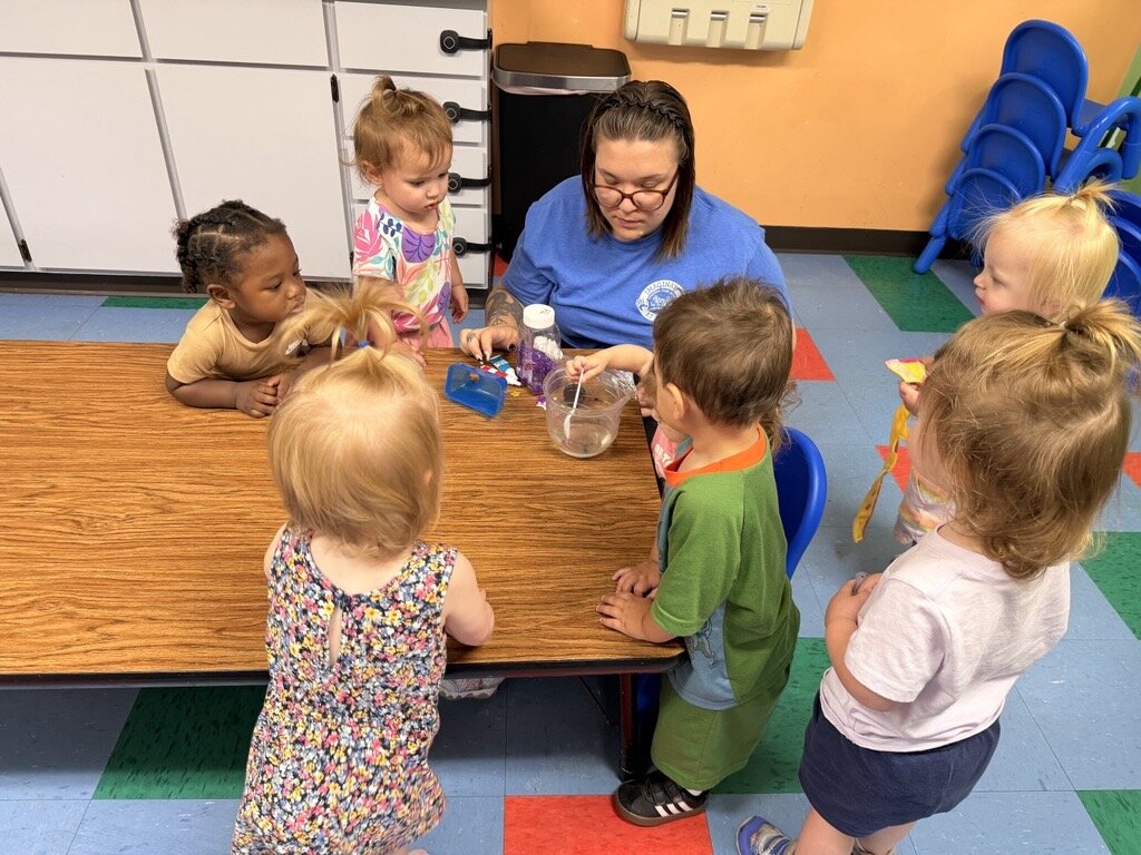 Emerging toddlers in action at Creative Kids Academy Toddlers exploring a sensory activity with their teacher at Creative Kids Academy