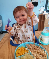 Toddler happily eating a balanced meal at Creative Kids Academy
