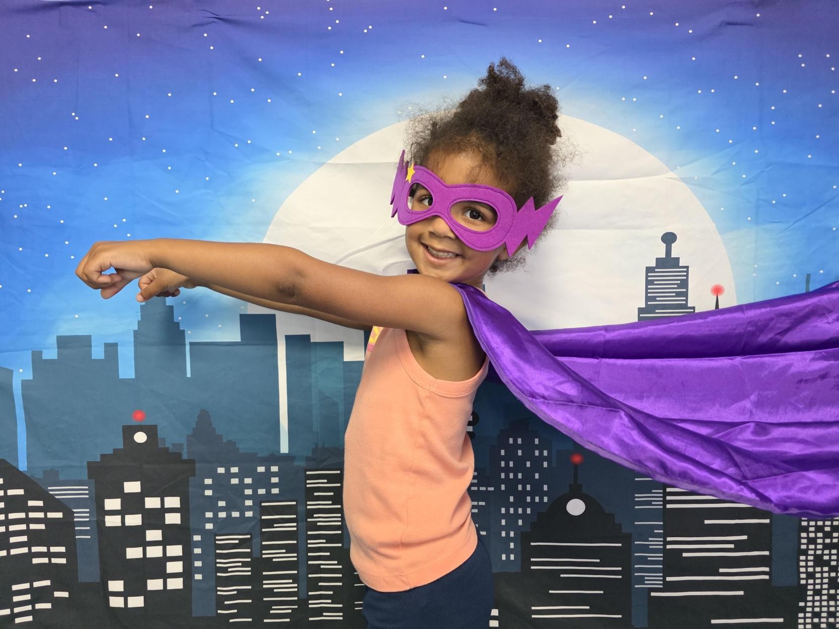 Preschooler flying in a superhero cape at Creative Kids Academy