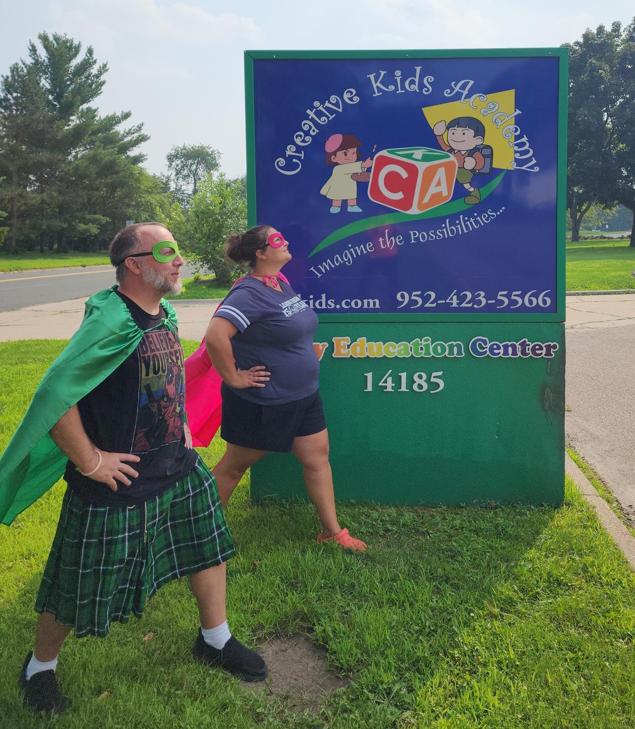 CKA staff dressed as superheroes posing in front of the Creative Kids Academy sign
