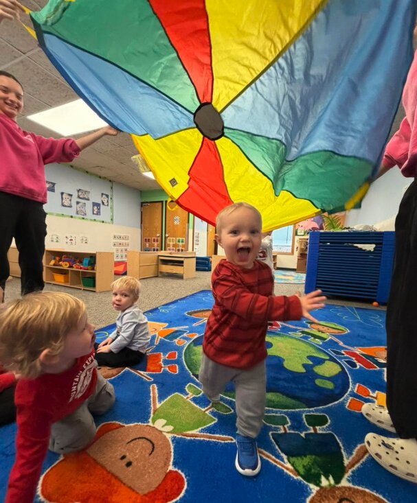 Toddlers playing with a parachute at Creative Kids Academy