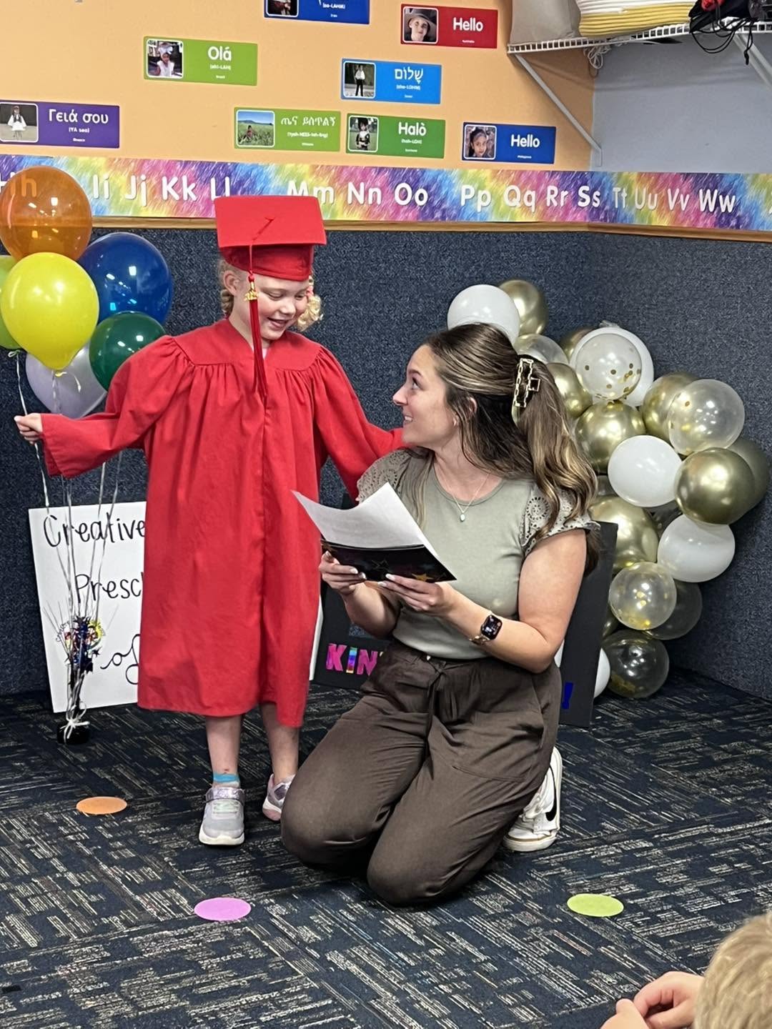 A CKA preschool graduate with her teacher celebrating graduation