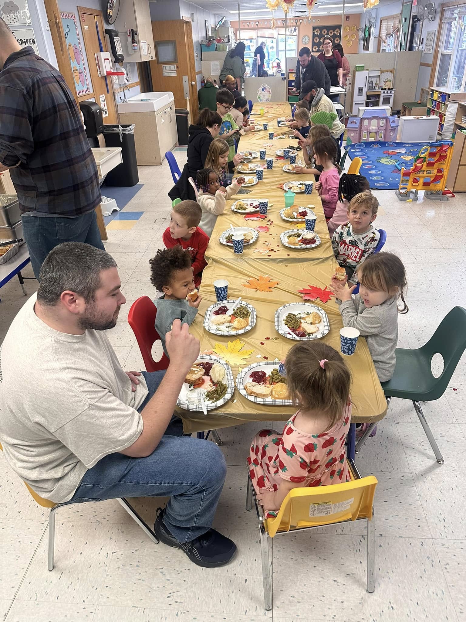 Families and children enjoying a Thanksgiving feast together at Creative Kids Academy