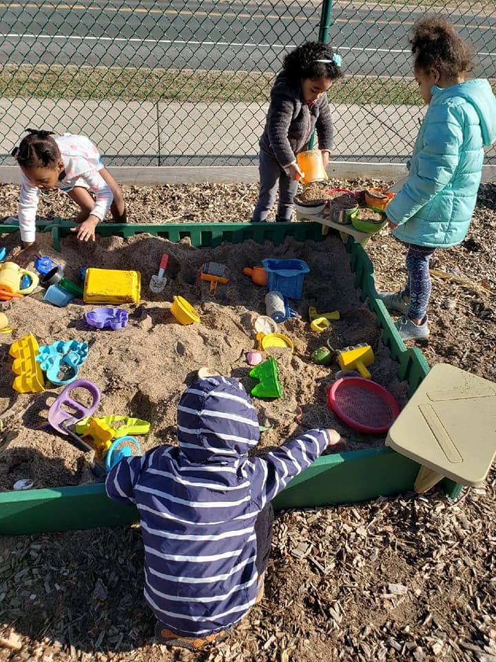 Children playing together in the sandbox during outdoor play