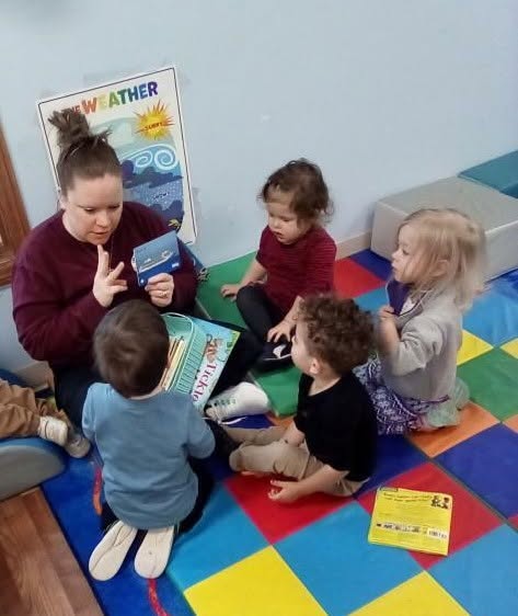 A teacher reading to a group of children during circle time at Creative Kids Academy Maplewood