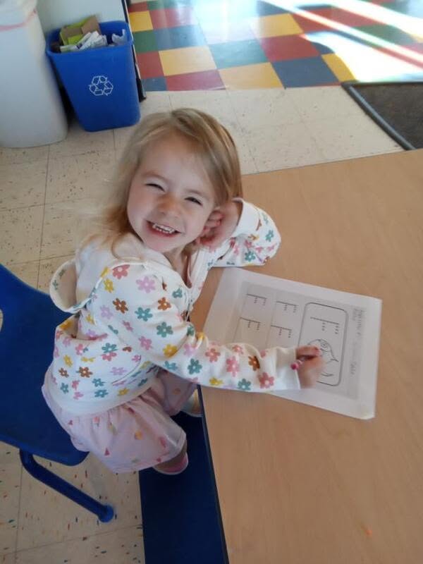 A preschooler practicing writing at the table at Creative Kids Academy Minnetonka