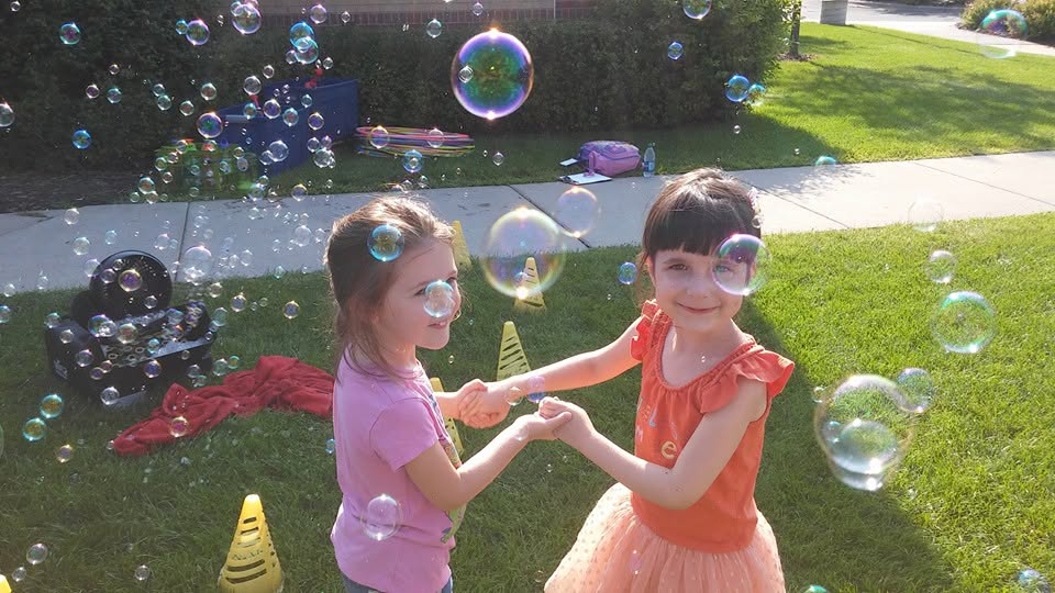 Two friends laughing together among bubbles at Creative Kids Academy Mounds View