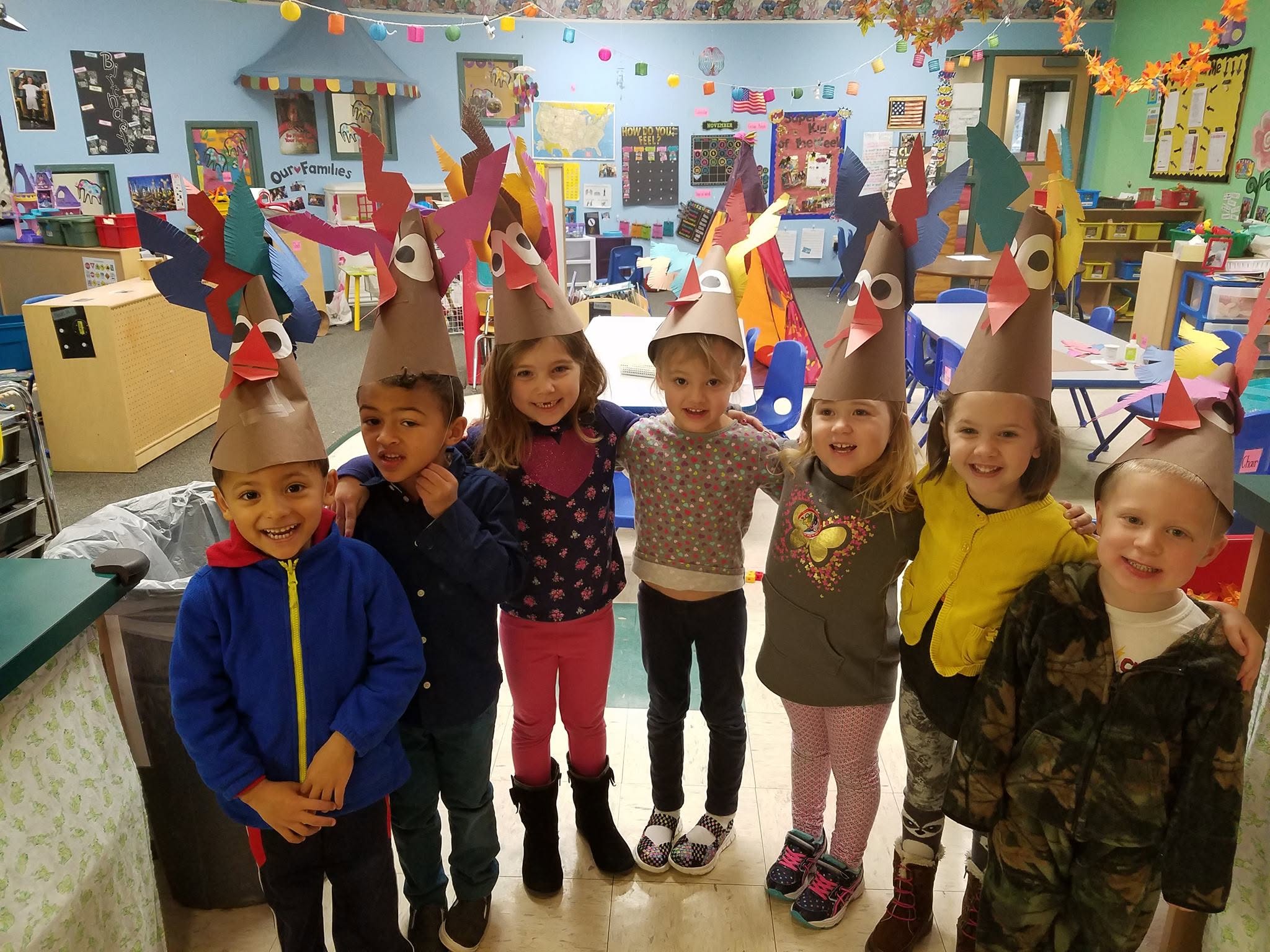 Children showing off their turkey hat crafts during a Thanksgiving activity