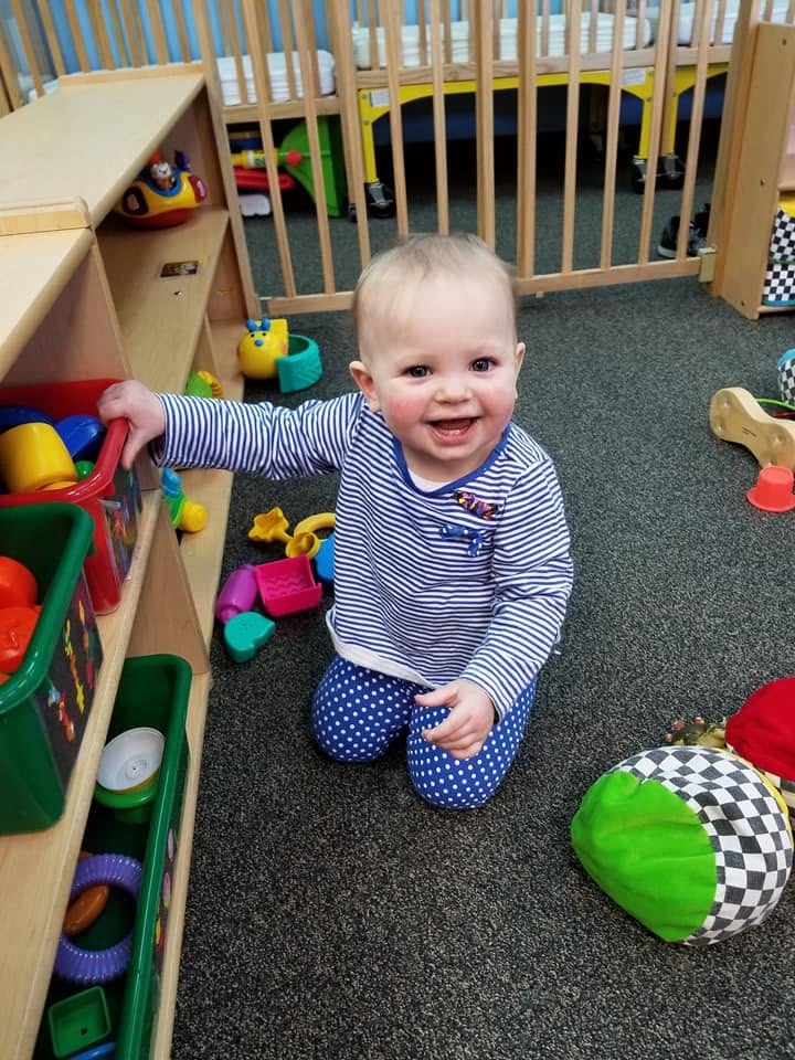 A happy toddler exploring toys in the infant classroom at Creative Kids Academy Mounds View