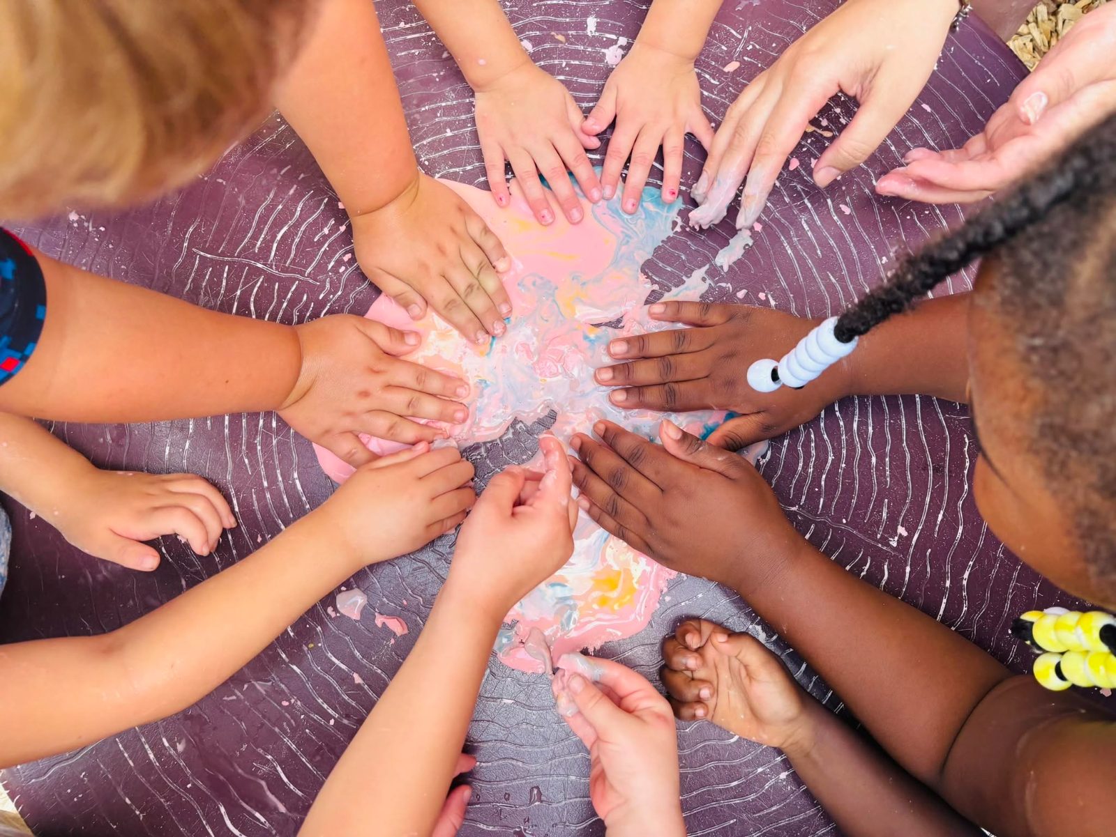 Children and teachers mixing colors together during sensory play at Creative Kids Academy Anoka