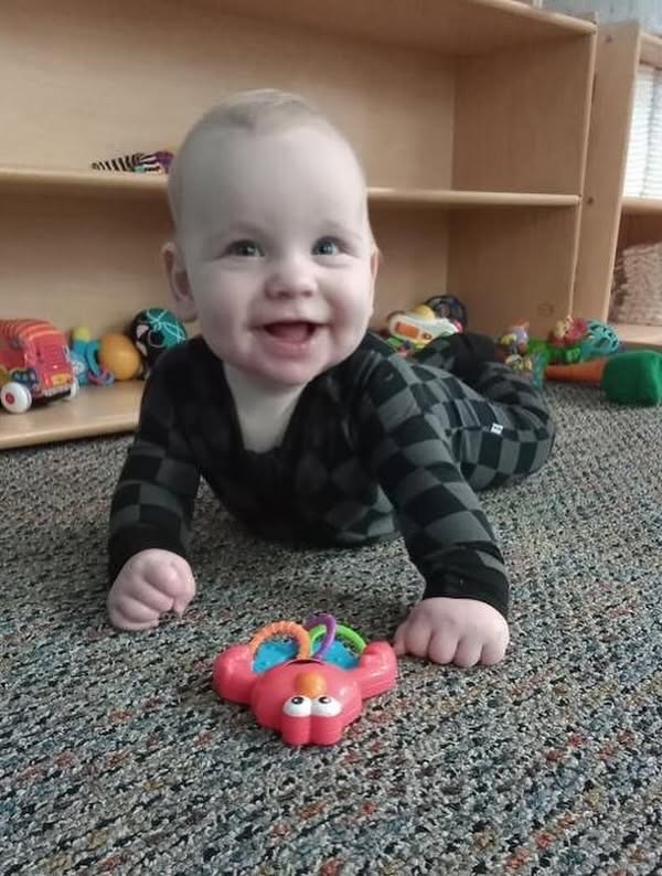 An infant crawling and reaching for a toy at Creative Kids Academy Orono