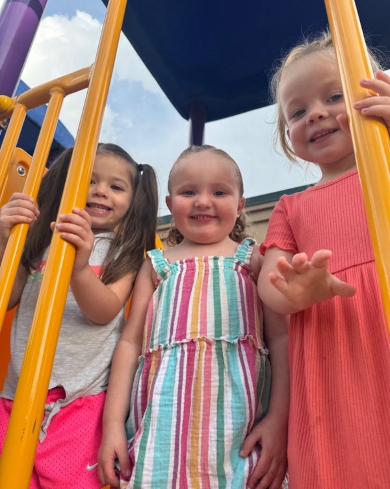 Three smiling preschoolers on playground equipment at Creative Kids Academy Centerville