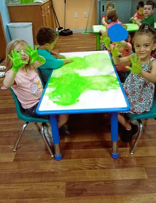 Children showing off their green painted hands after an art activity at Creative Kids Academy Maplewood