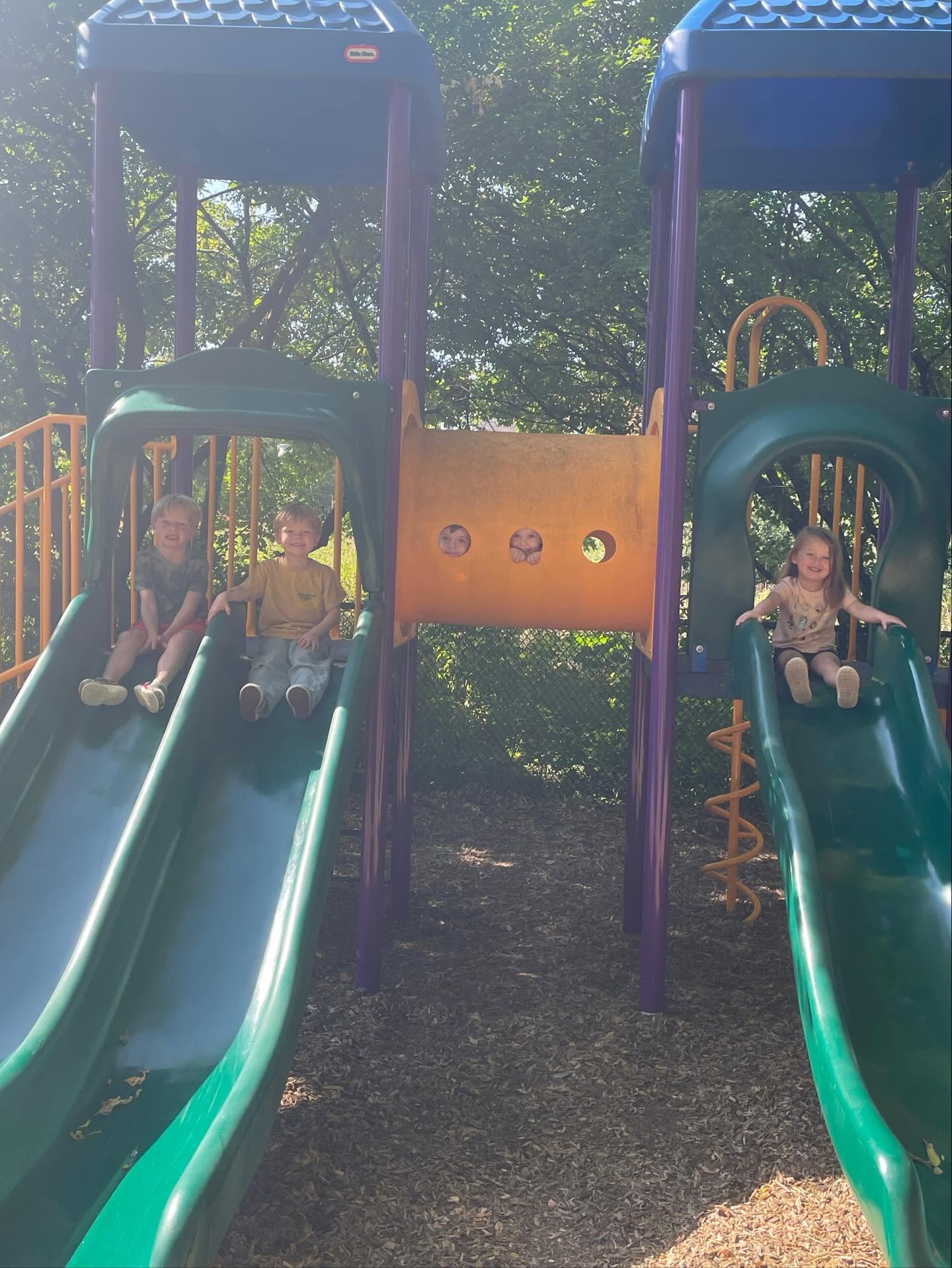 Children playing on the outdoor playground slides at Creative Kids Academy Orono