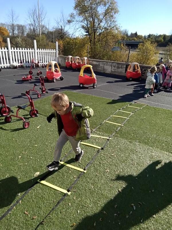 A preschooler running an obstacle course on the playground at Creative Kids Academy Minnetonka