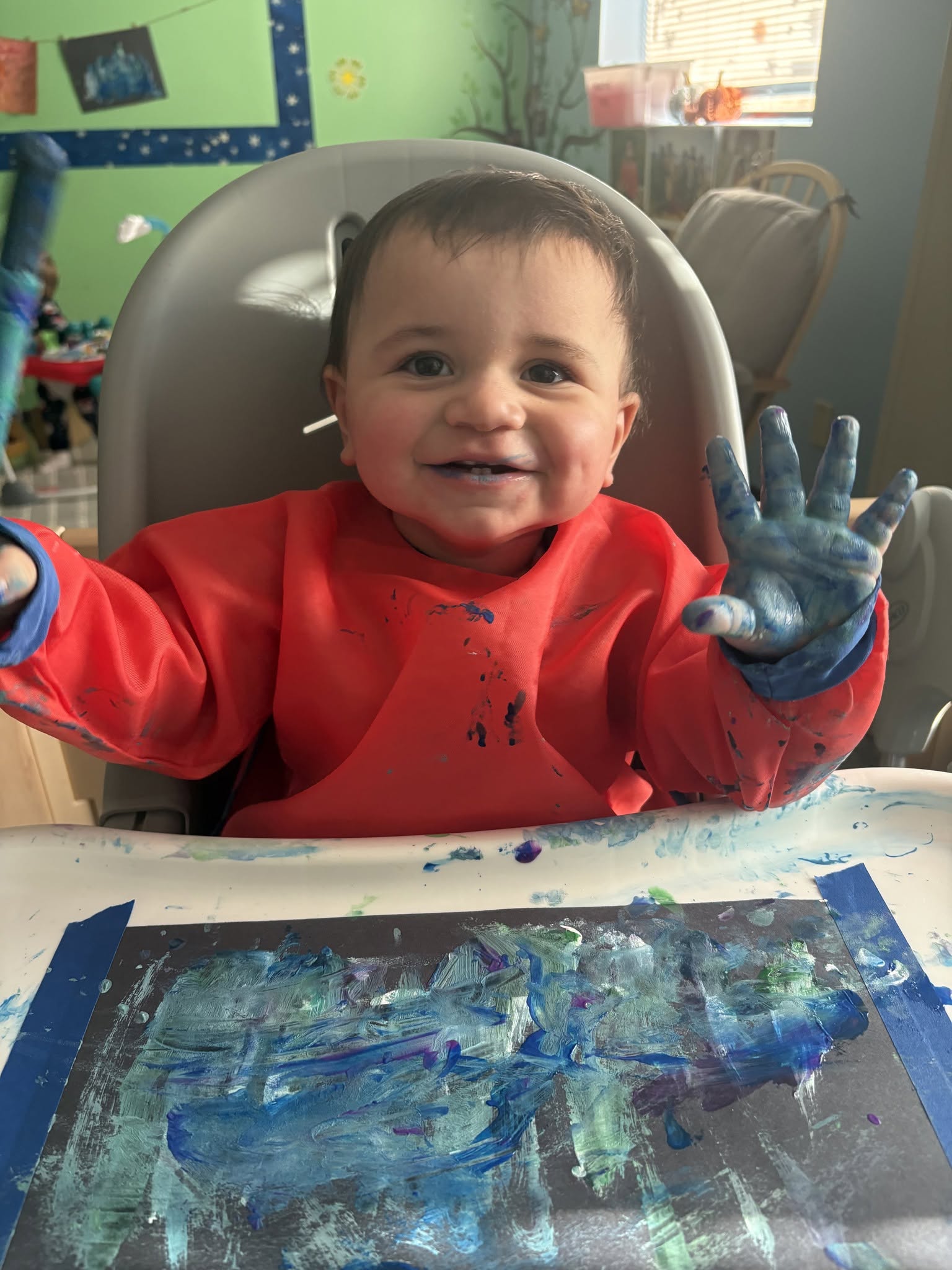 Smiling infant finger painting at Creative Kids Academy Anoka