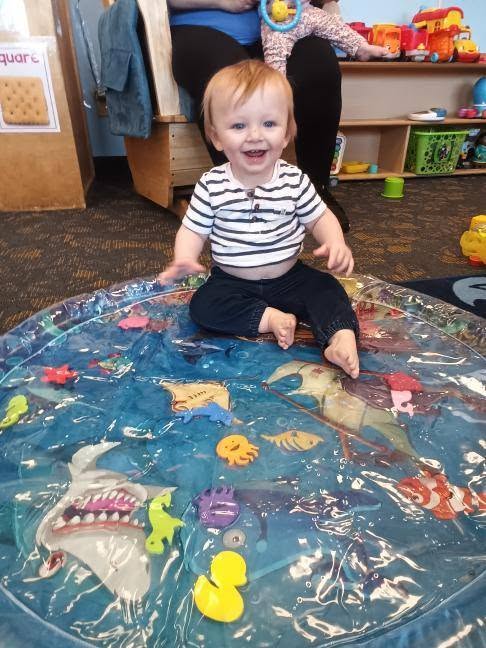 A toddler playing with a water sensory mat during activity time at Creative Kids Academy Lexington