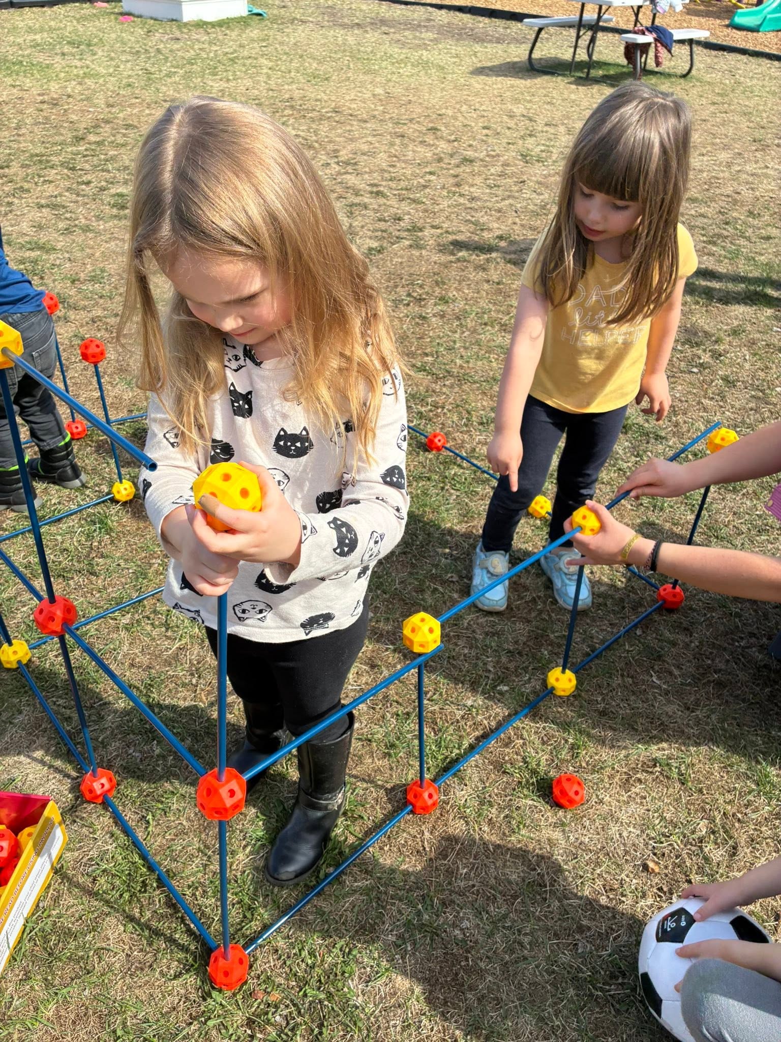 Preschoolers building a large geodesic dome together during outdoor STEM play at Creative Kids Academy Elk River