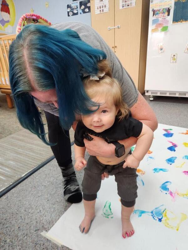 A teacher walking with a toddler