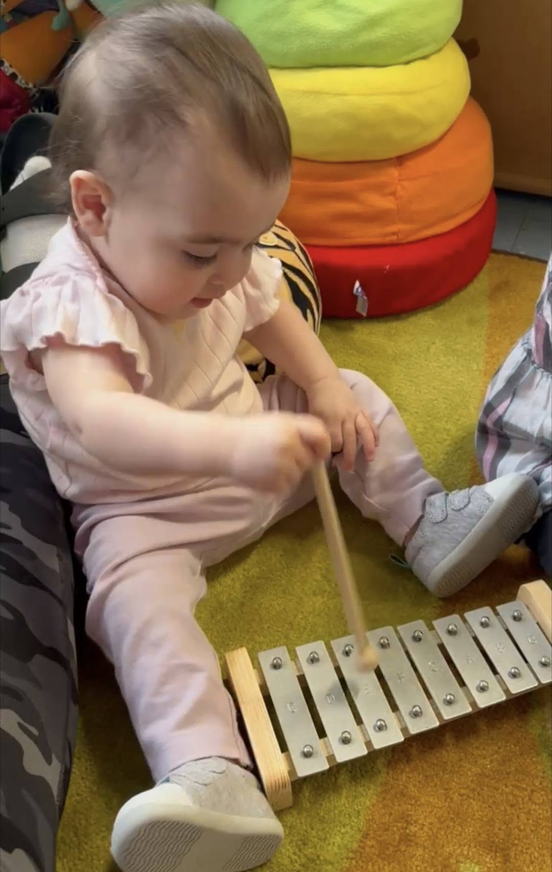 An infant playing a xylophone during music time at Creative Kids Academy Maple Grove