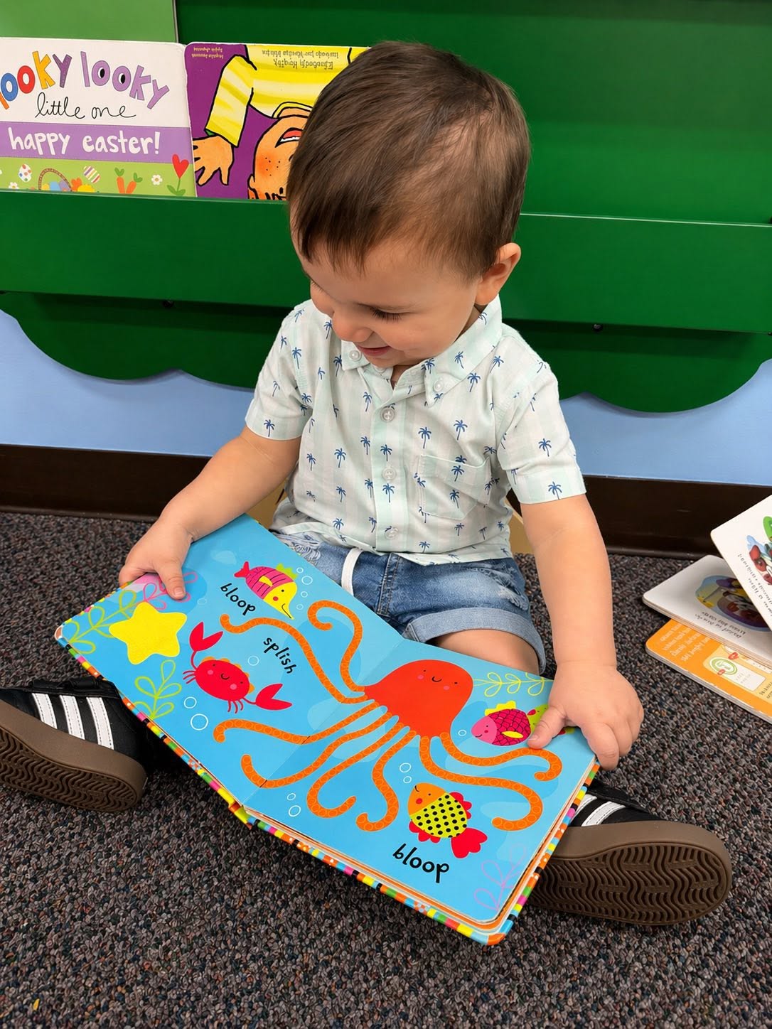 Toddler exploring a picture book in the reading corner