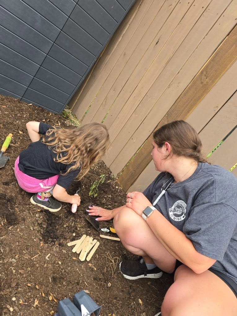 A teacher and child gardening together outside at Creative Kids Academy Lexington