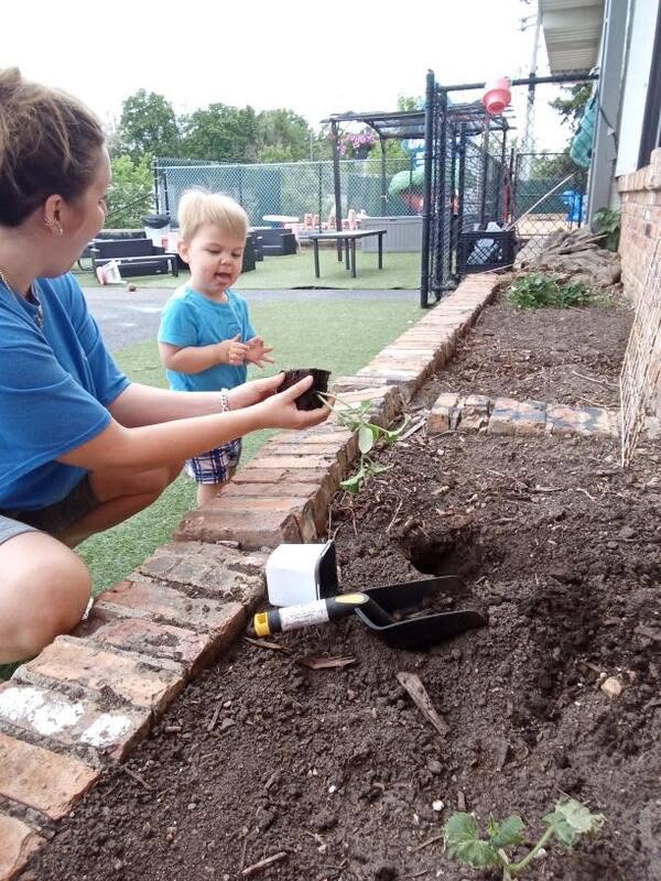 A toddler gardening with a teacher at Creative Kids Academy Minnetonka