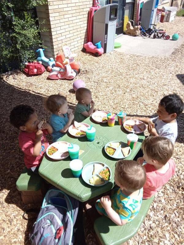 Children enjoying lunch together at an outdoor picnic table at Creative Kids Academy Lexington