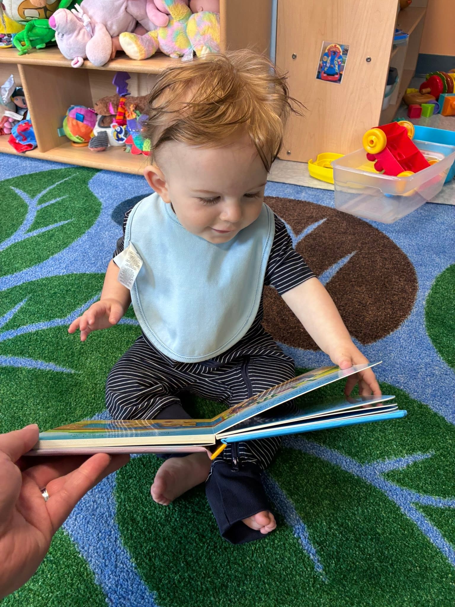 An infant exploring a board book during quiet playtime at Creative Kids Academy Elk River