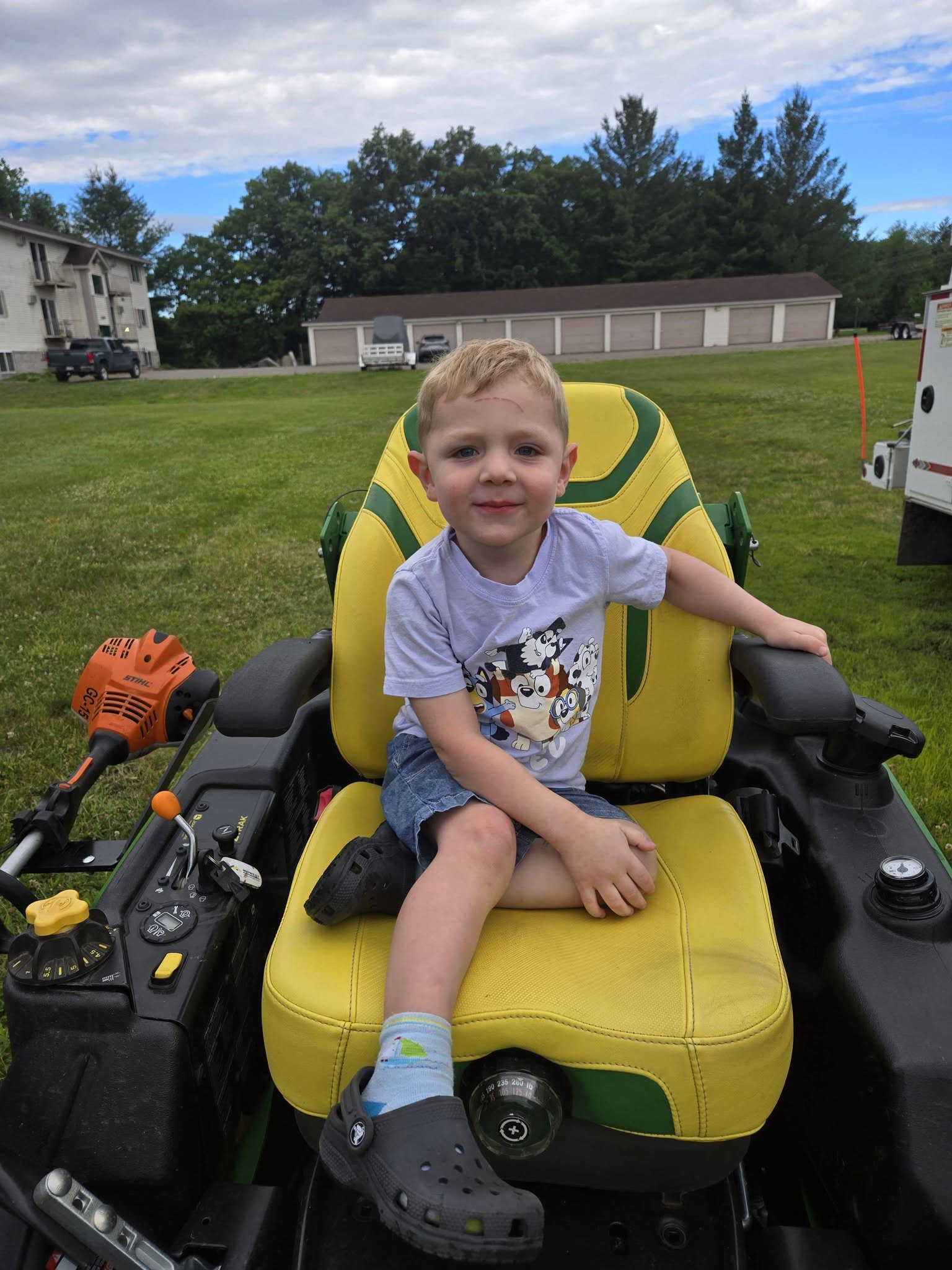 A preschooler smiling while sitting on a riding lawn tractor at Creative Kids Academy Zimmerman