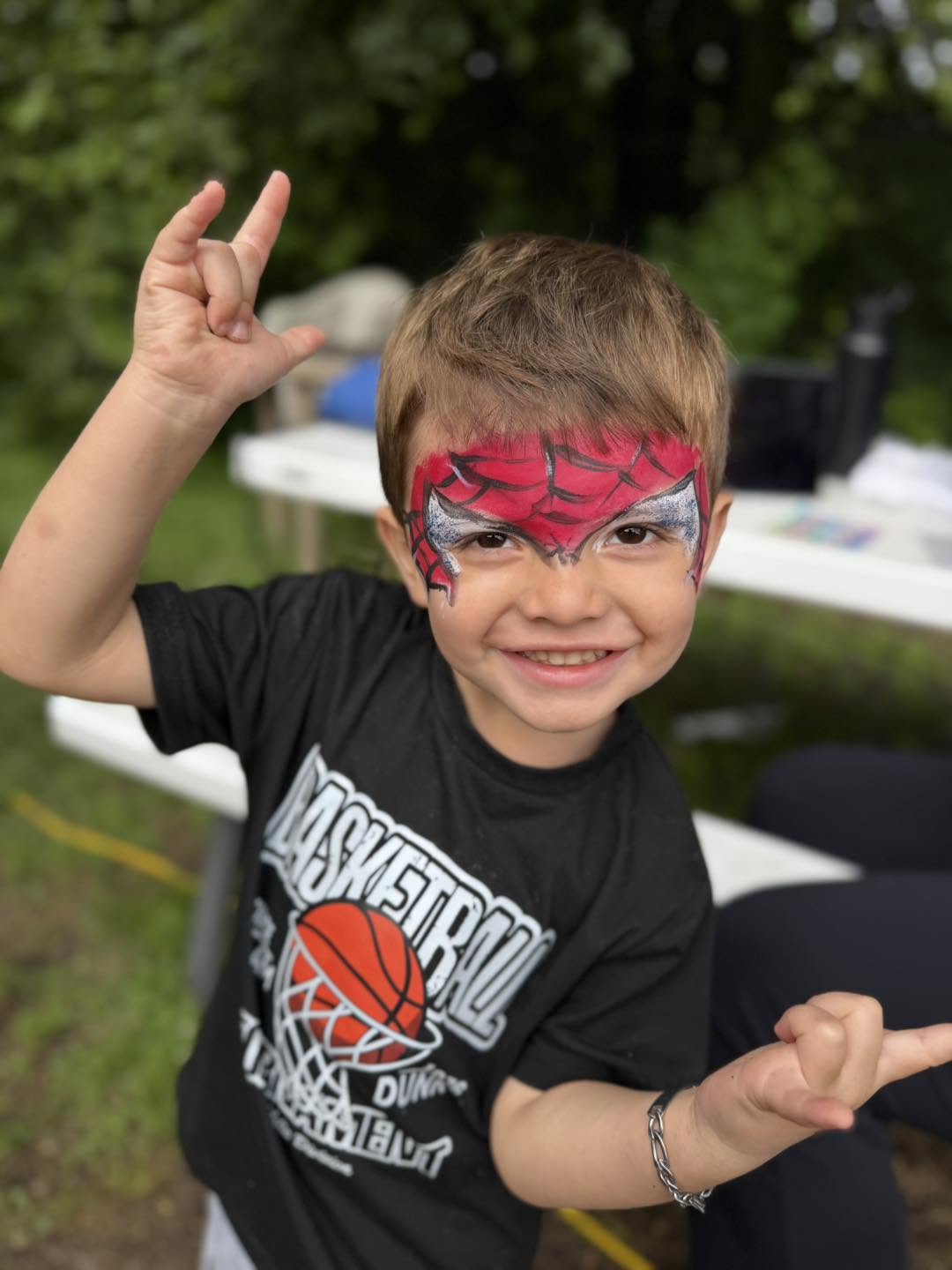 A preschooler showing off his spider-web face paint at an outdoor event at Creative Kids Academy Elk River on 10