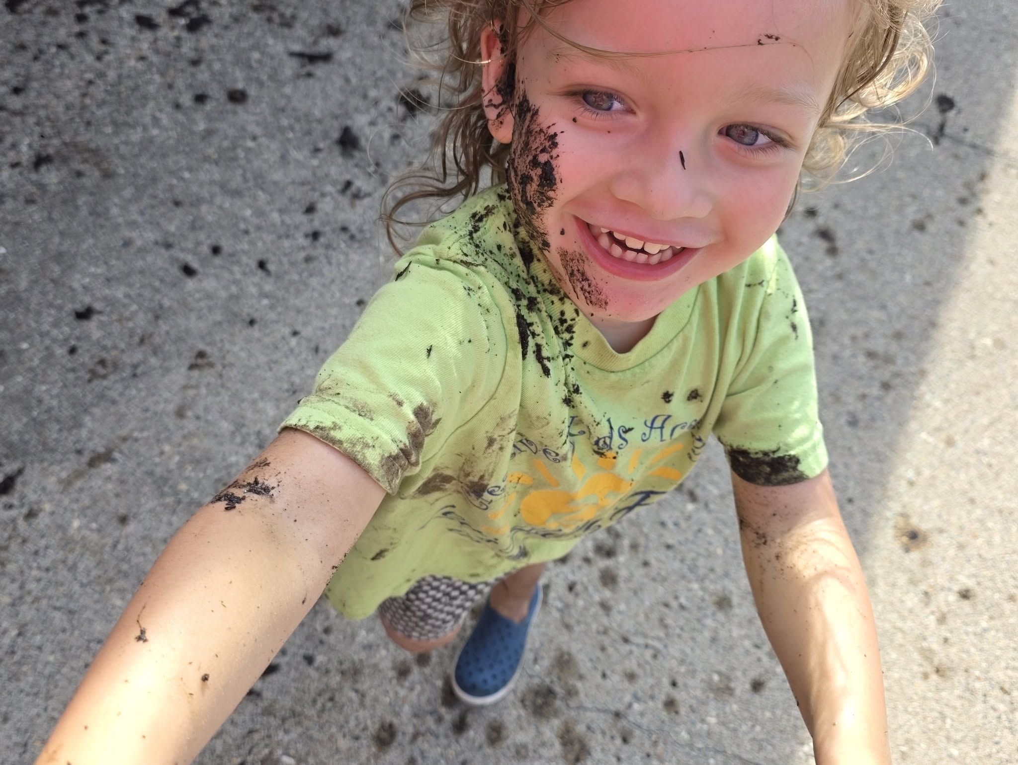 A child laughing outside after messy play