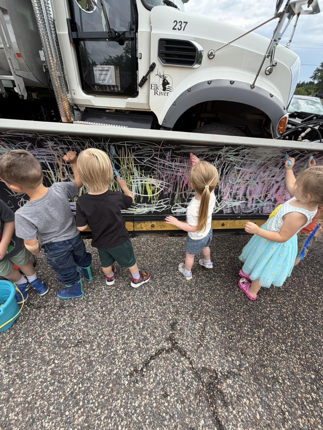 Children drawing with chalk on a City of Elk River truck during a community visit at Creative Kids Academy Elk River on 10