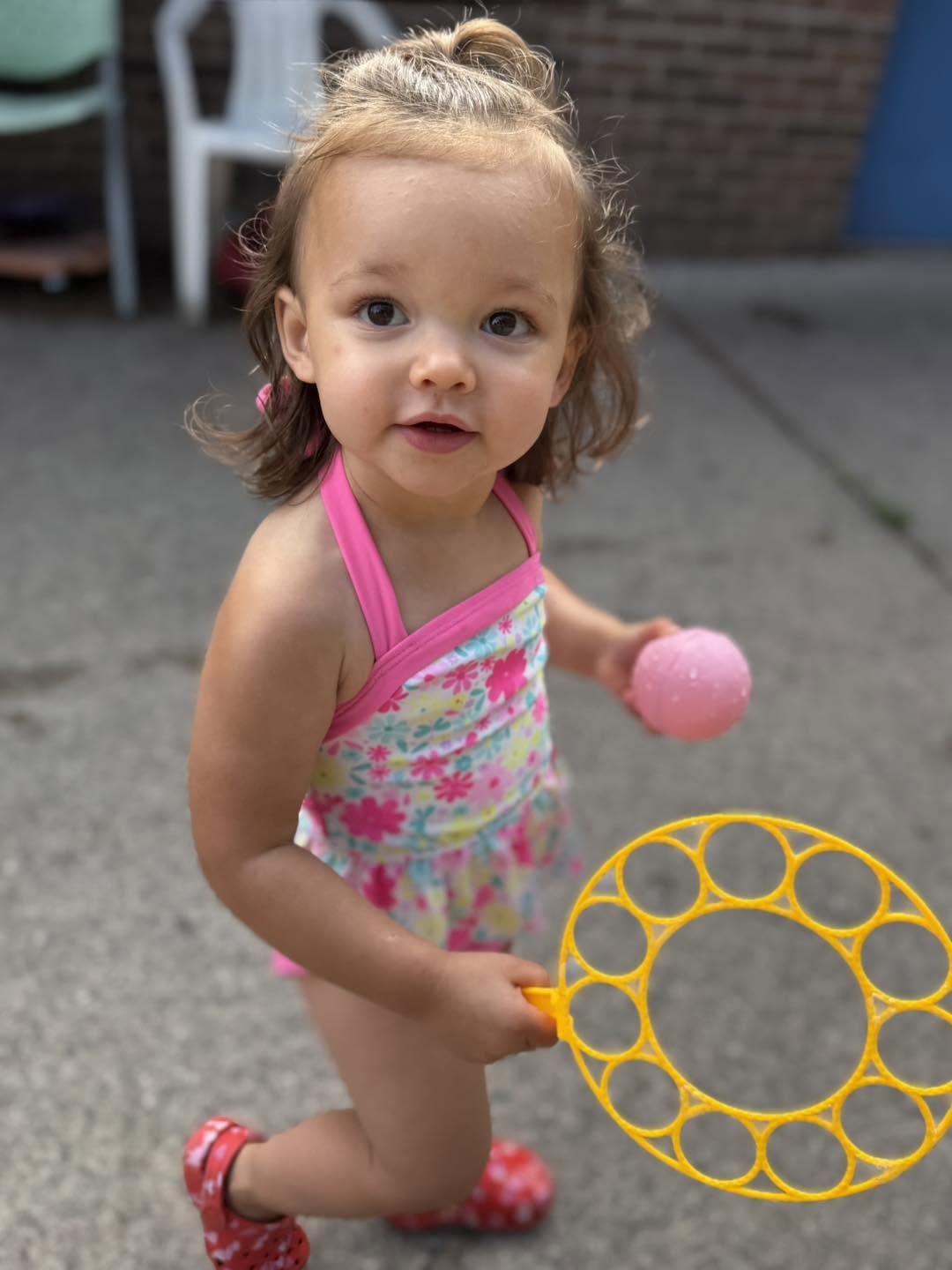 A toddler playing with bubbles and a ball outdoors at Creative Kids Academy Elk River on 10