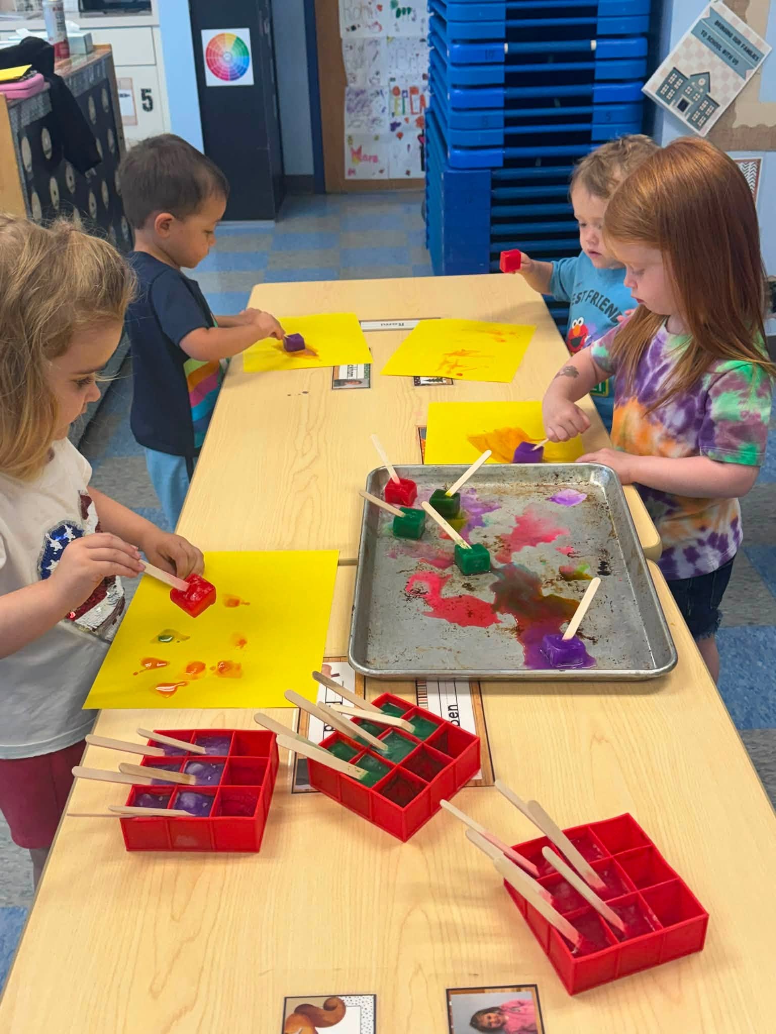 Preschoolers exploring color mixing with melting ice cubes at Creative Kids Academy Centerville