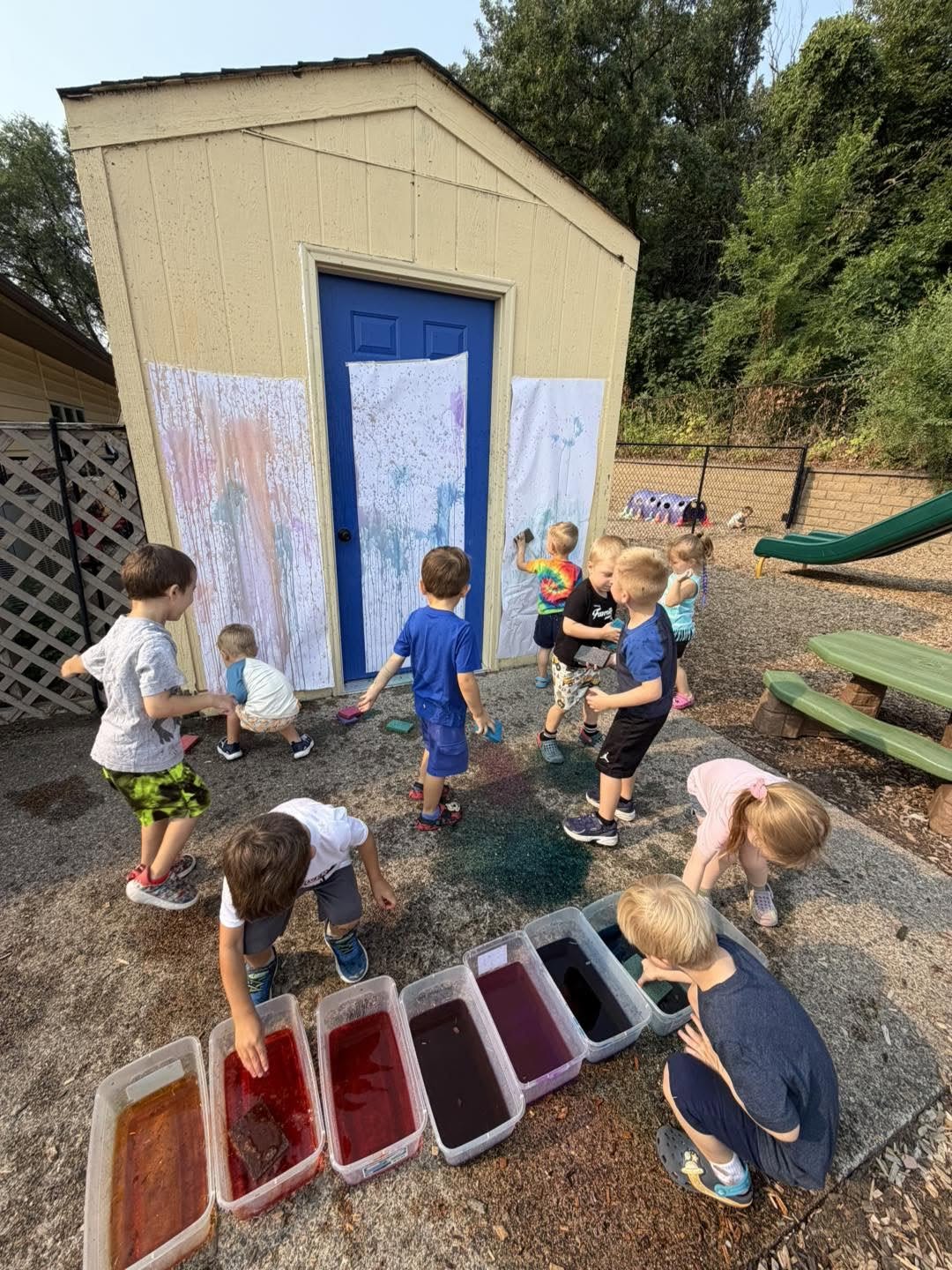 Preschoolers painting a mural on an outdoor shed together at Creative Kids Academy Elk River on 10