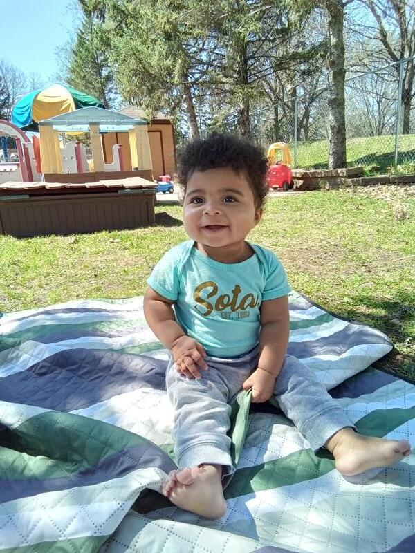 Smiling infant enjoying outdoor time on the playground at Creative Kids Academy Apple Valley