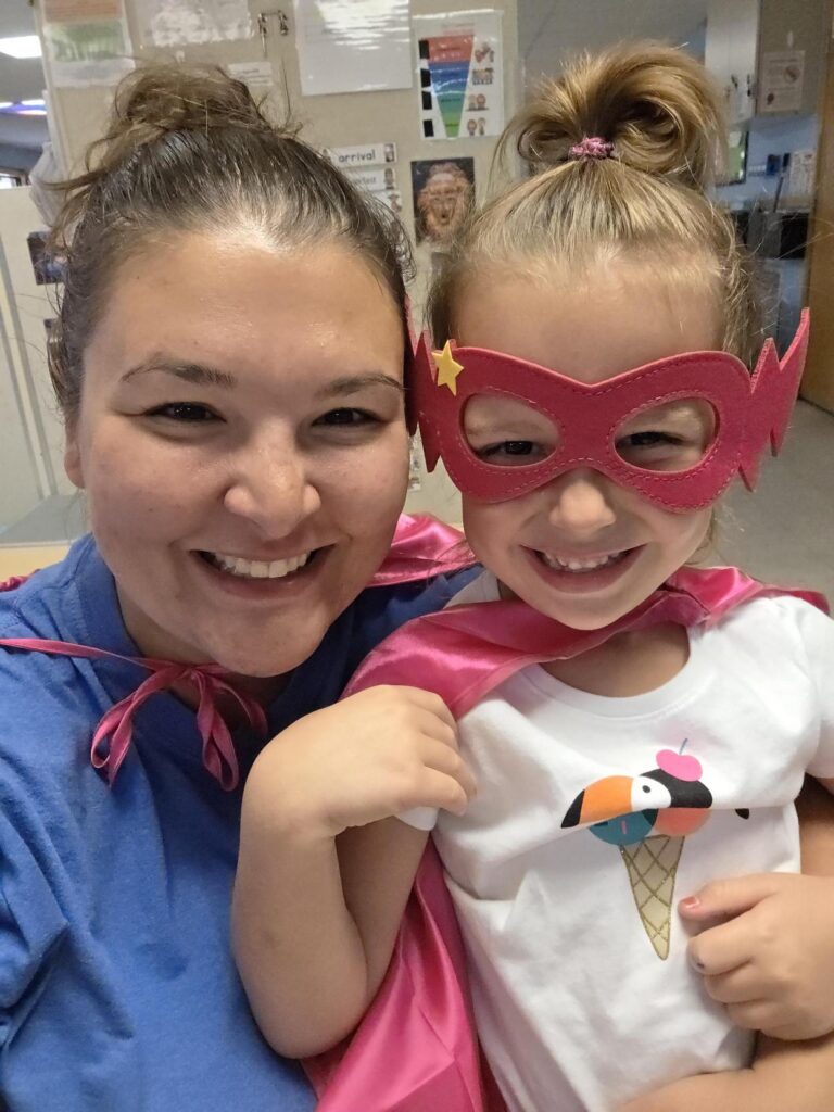 A Creative Kids Academy teacher and a child wearing superhero capes and masks