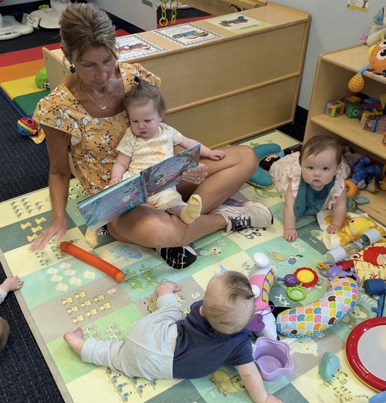 Teacher reading a book with infants during group time