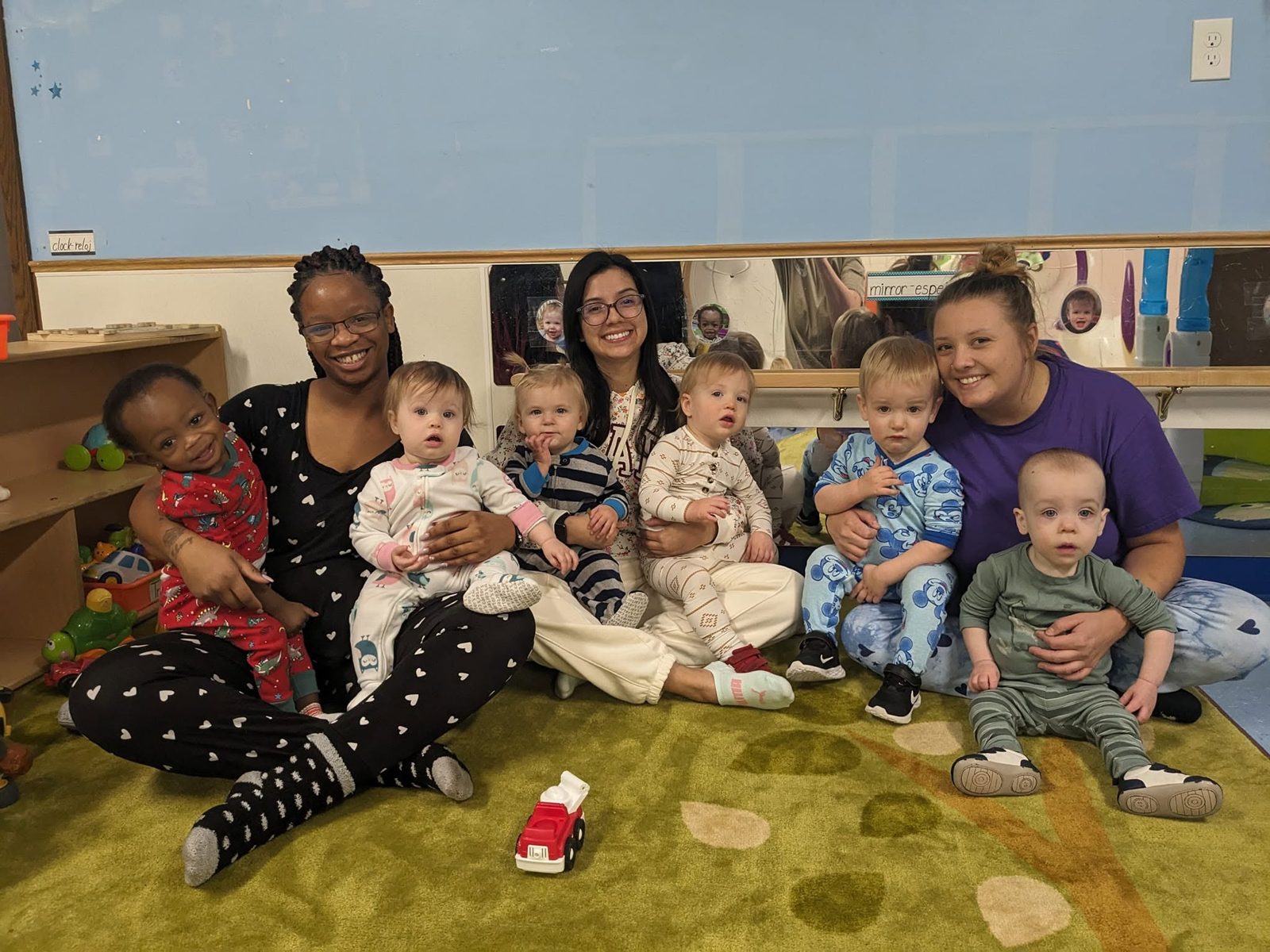 Three smiling Creative Kids Academy infant teachers holding babies in the classroom