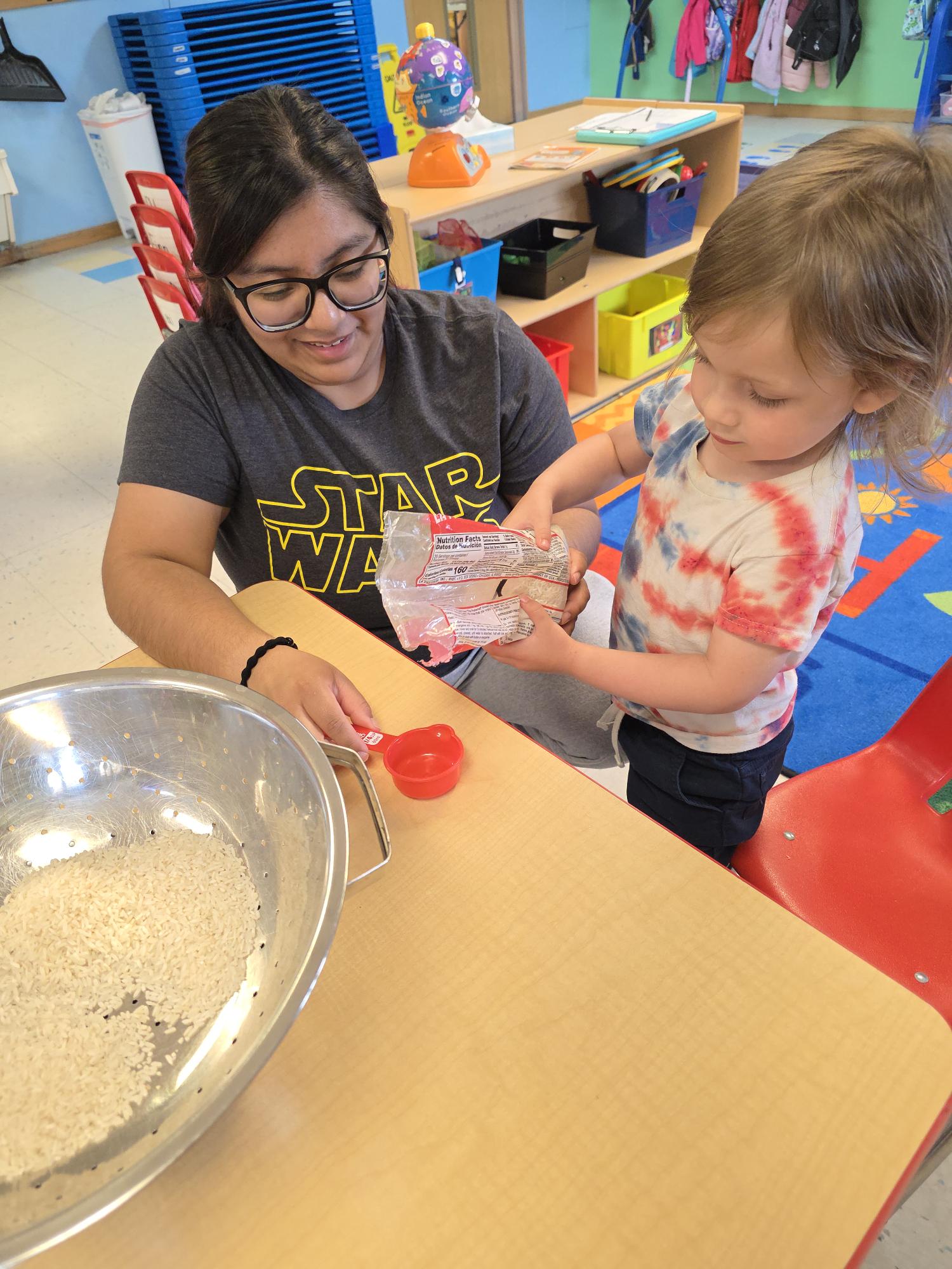 Teacher and toddler measuring rice together during a sensory activity
