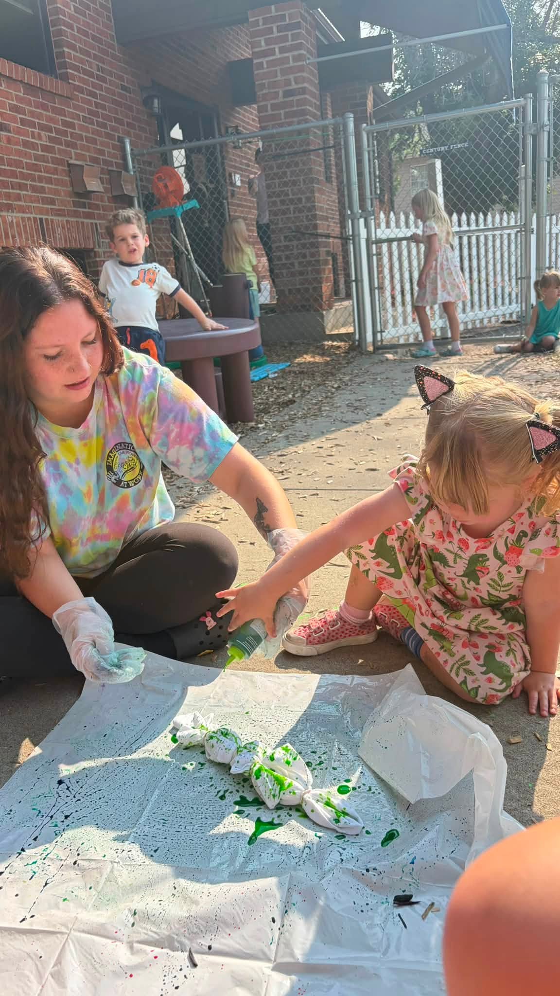 A teacher and children painting together outside at Creative Kids Academy Anoka