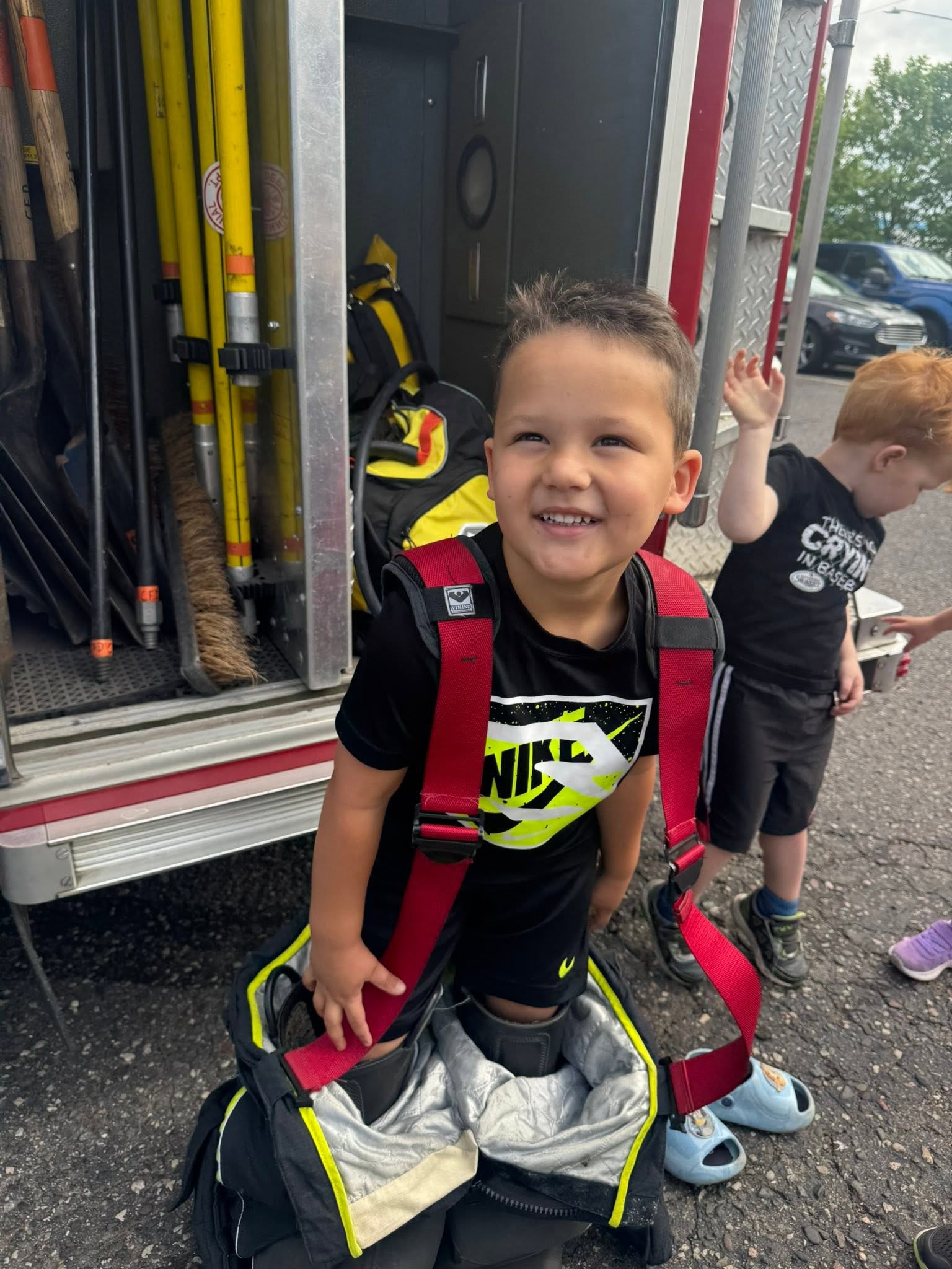 Preschooler trying on firefighter gear at Creative Kids Academy Centerville