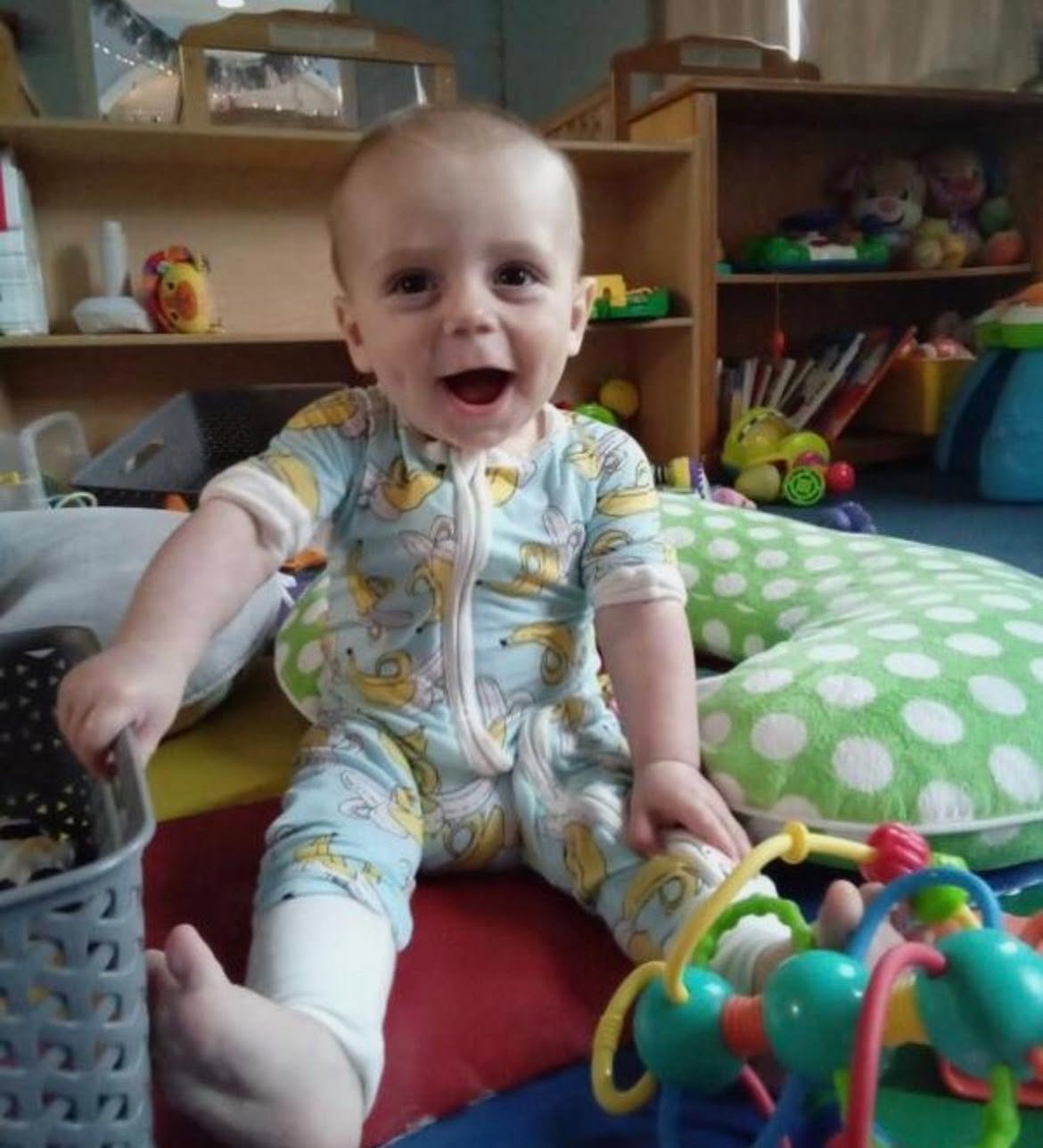 Smiling baby sitting up and playing in the infant room at Creative Kids Academy Minnetonka