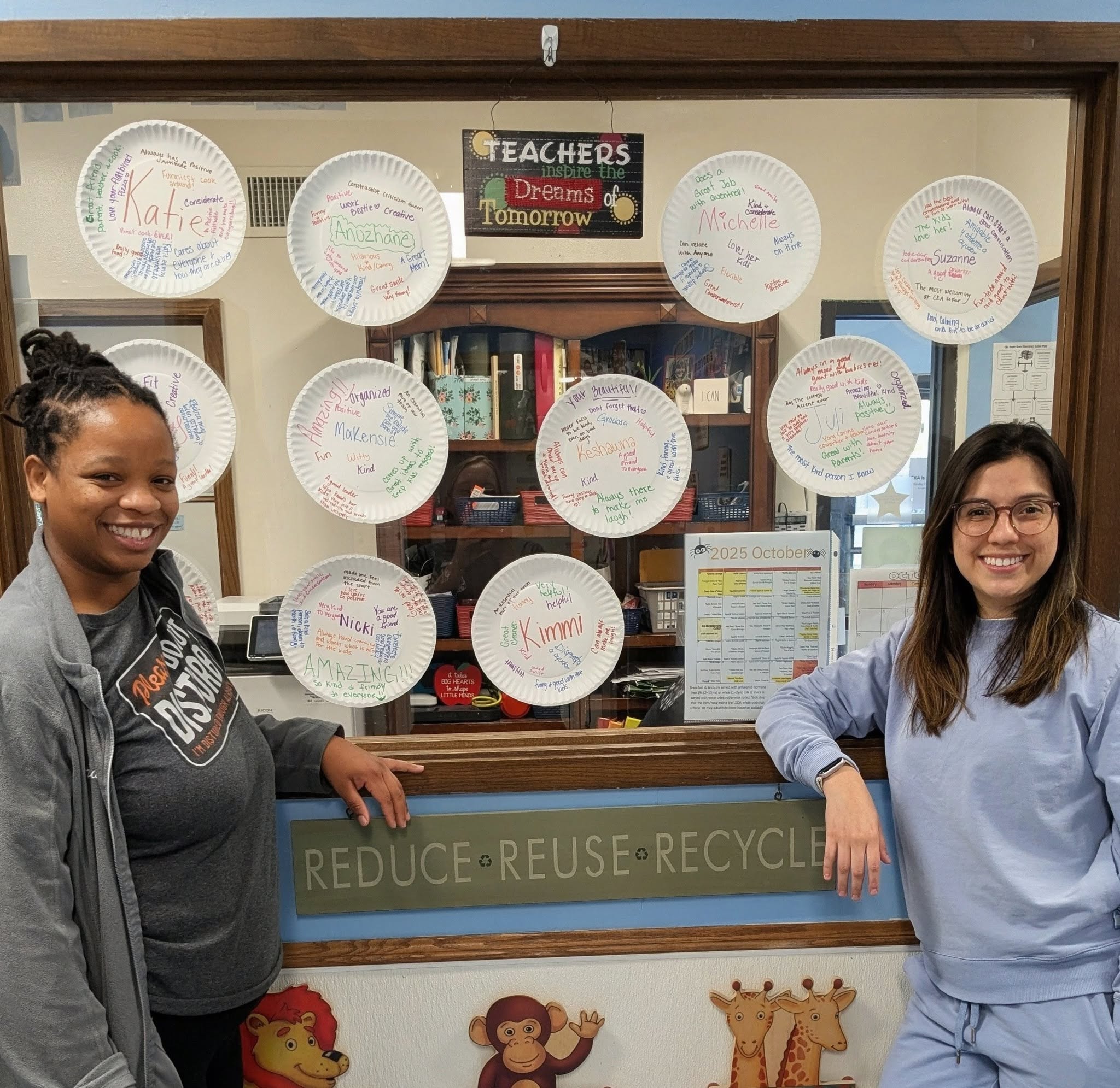 Teachers beside a wall of handwritten compliment plates at Creative Kids Academy