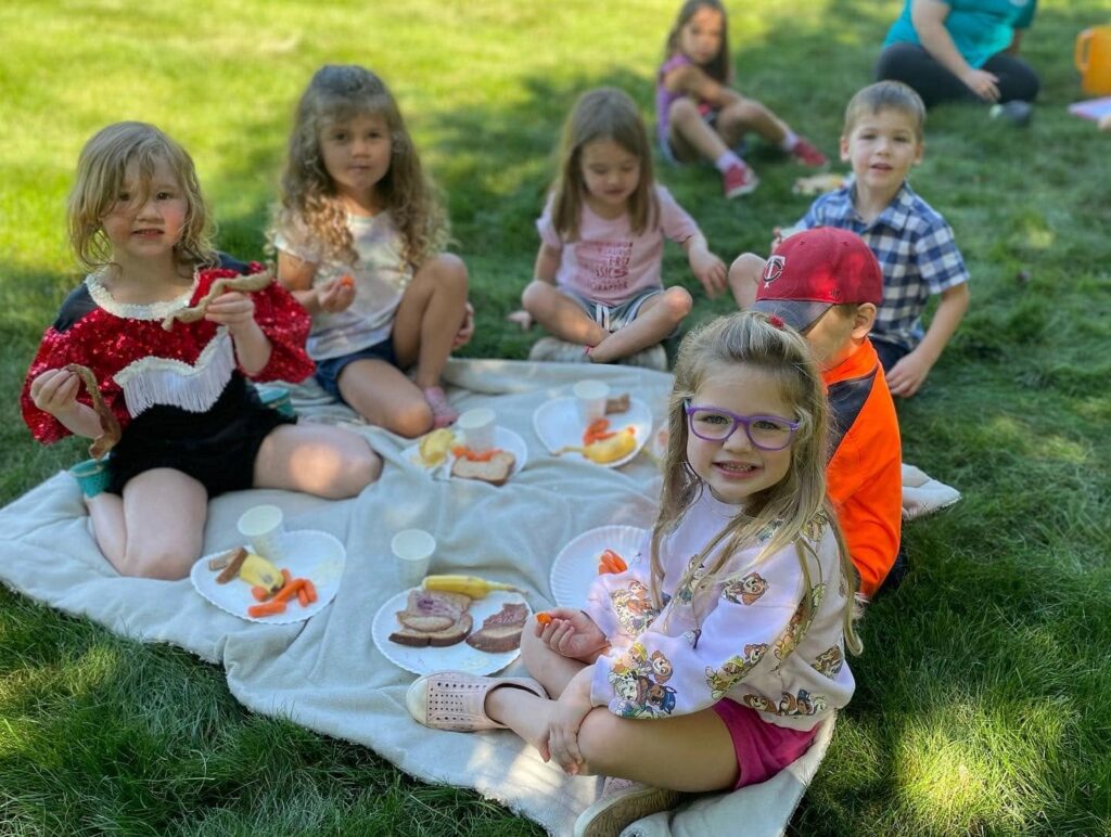 Children enjoying a family-style outdoor picnic snack at a Creative Kids Academy center